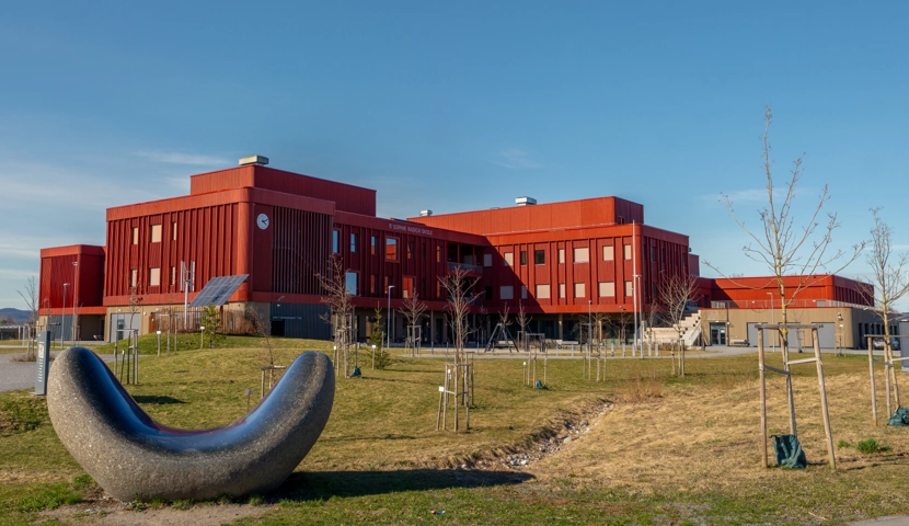 En stor rød bygning med en metallskulptur foran.