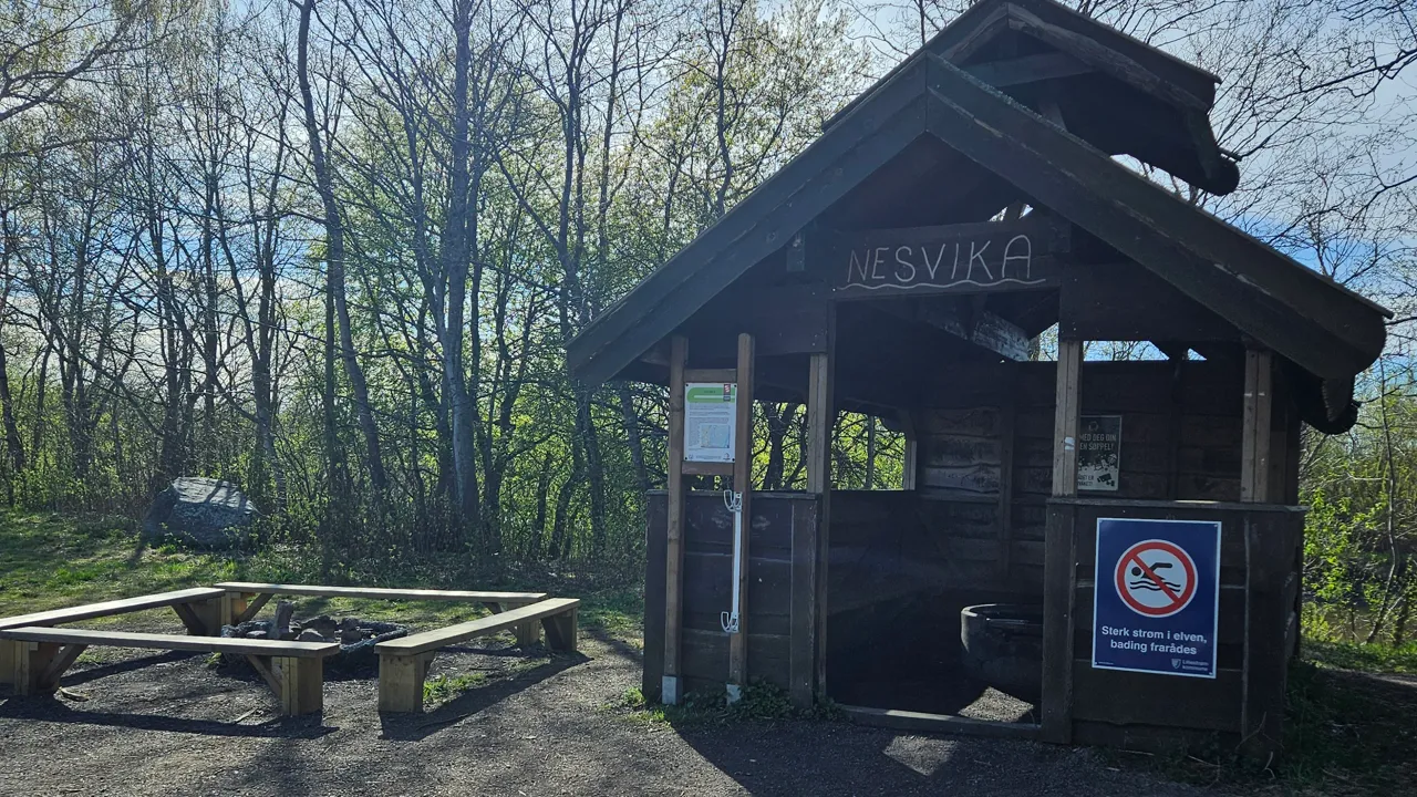 Et lite trehytte med en bålplass.