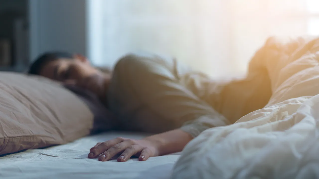 En dame som ligger i sengen med hodet på puten.