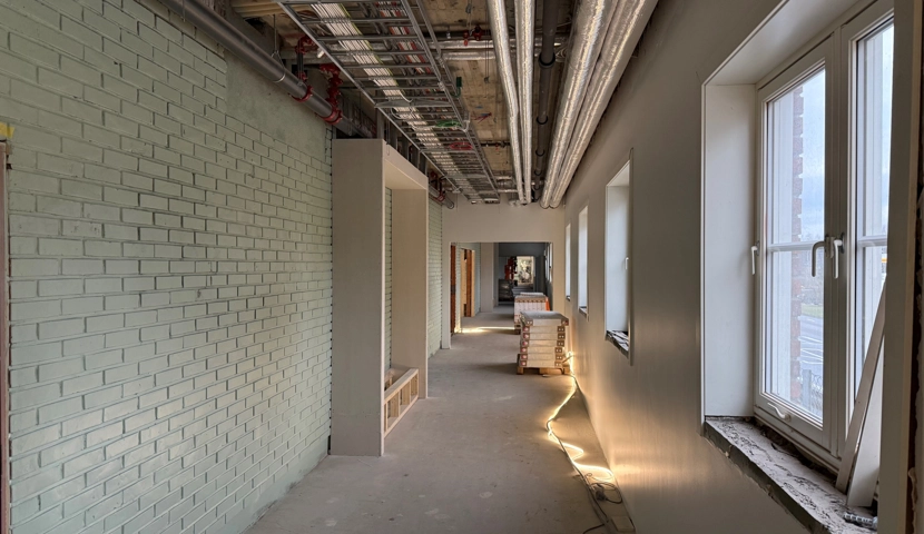 En lang gang med en hvit murvegg.