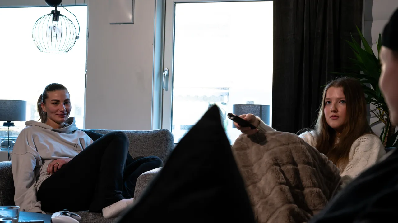 En gruppe mennesker som sitter i en sofa i en stue.
