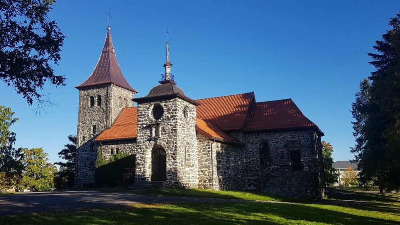 En gammel steinkirke med rødt tak.