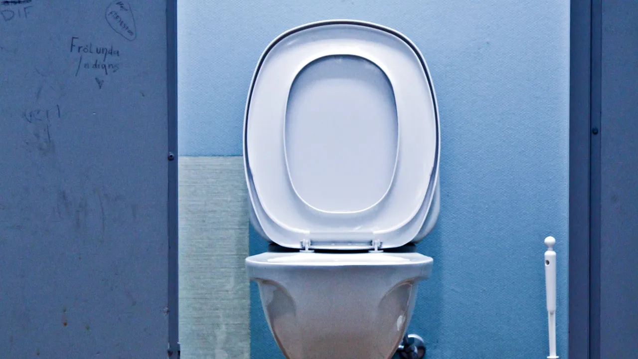 En bås på et bad med åpen dør inn til toalett