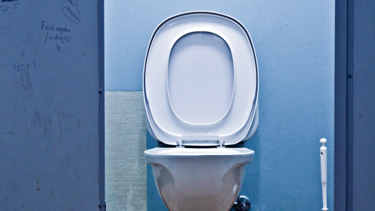 En bås på et bad med åpen dør inn til toalett