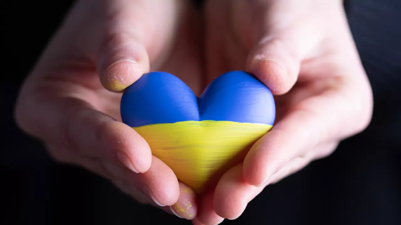 To hender holder et hjerte malt i gult og blått