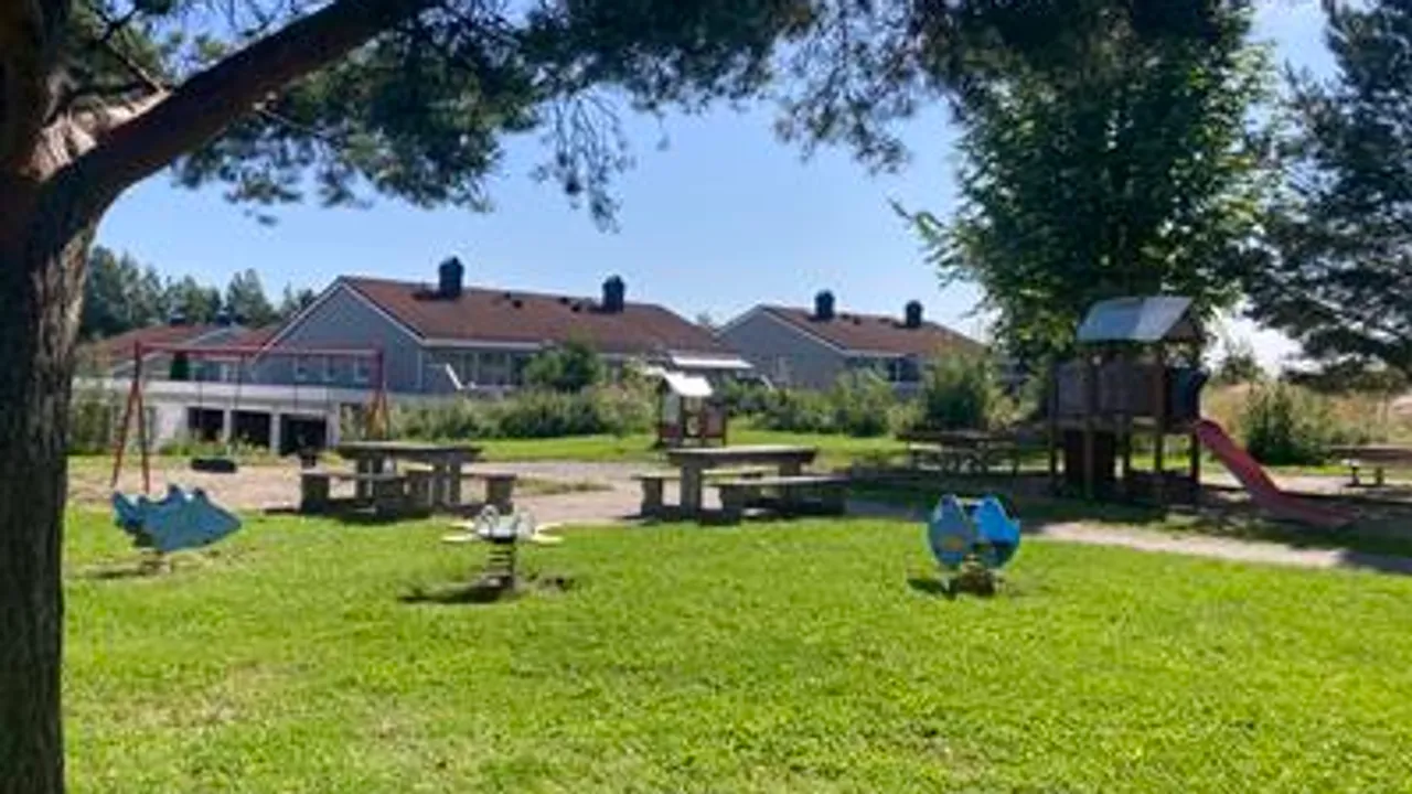 En park med lekeplass og piknikbord.