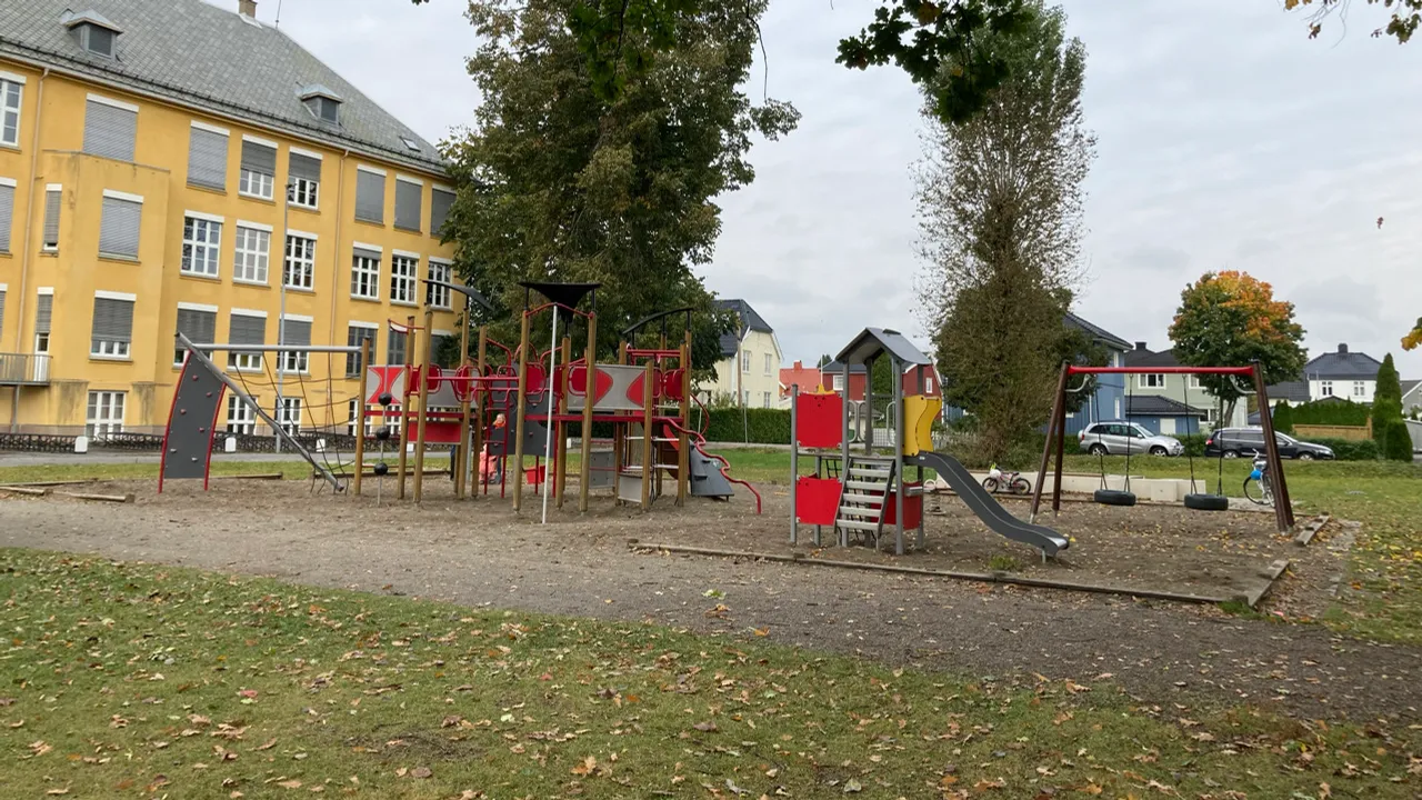 En lekeplass foran en stor gul bygning.